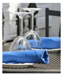 Image of a dining table with wine glass and blue serviette. 