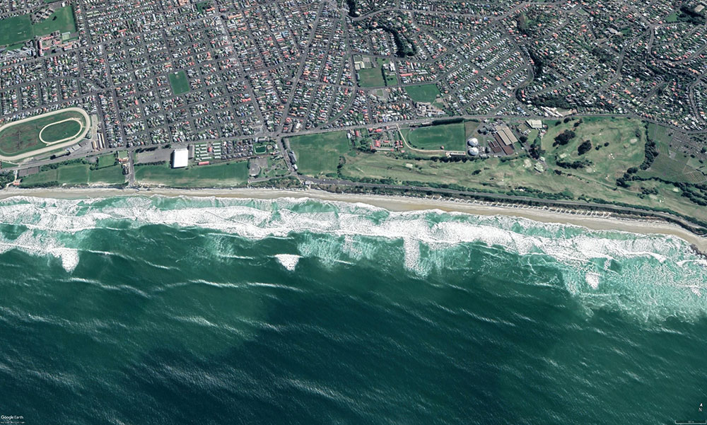 An aerial view of the coast showing the location of cross-shore currents (rips), the water is a lighter shade as it contains mobile sand